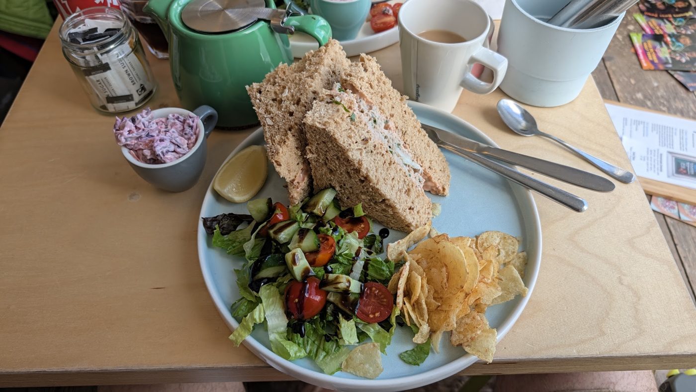 A sandwich with salad and crisps on a blue plate
